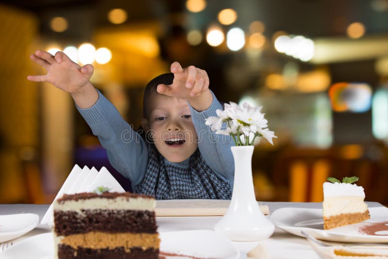 Ragazzino emozionante che raggiunge per una fetta di dolce fotografie stock Ragazzino emozionante che raggiunge per una fetta di dolce fotografie stock