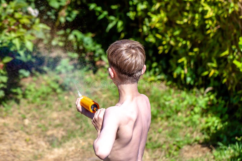 Ragazzino felice divertendosi con la pistola di getto nel giardino immagini stock libere da diritti Ragazzino felice divertendosi con la pistola di getto nel giardino immagini stock libere da diritti