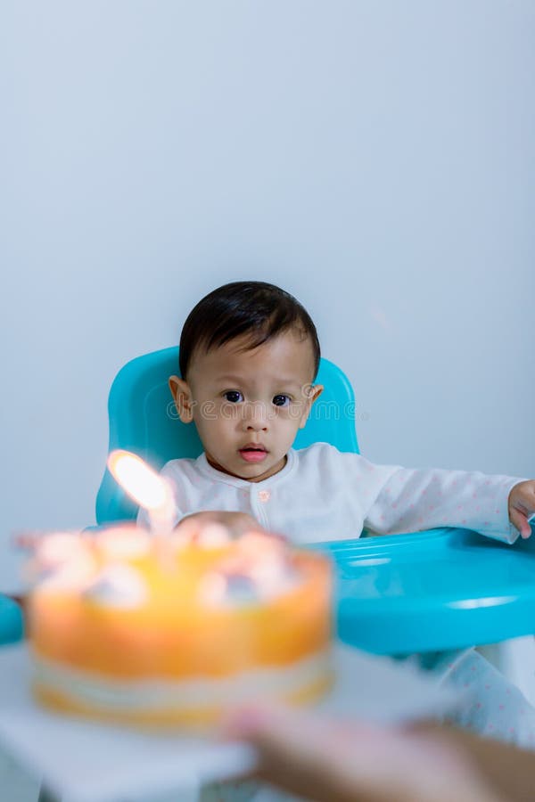 Ragazzino sveglio con la torta di compleanno che si siede sulla sedia nella sala immagini stock Ragazzino sveglio con la torta di compleanno che si siede sulla sedia nella sala immagini stock