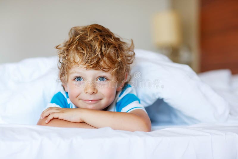 Ragazzo adorabile del bambino dopo il sonno nel suo letto bianco immagine stock libera da diritti Ragazzo adorabile del bambino dopo il sonno nel suo letto bianco immagine stock libera da diritti