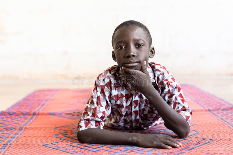 Ragazzo africano di etnia nera che si presenta come un modello sdraiato sul tappeto fotografia stock