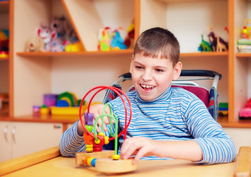 Ragazzo allegro con l'inabilità al centro di riabilitazione per i bambini con i bisogni speciali, risolvente puzzle logico
