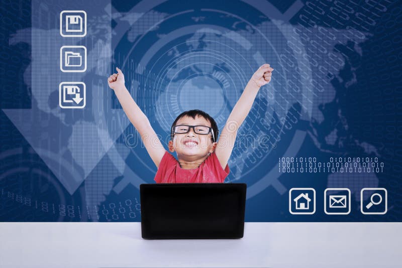 Ragazzo asiatico che vince facendo uso del computer portatile su fondo blu immagini stock Ragazzo asiatico che vince facendo uso del computer portatile su fondo blu immagini stock