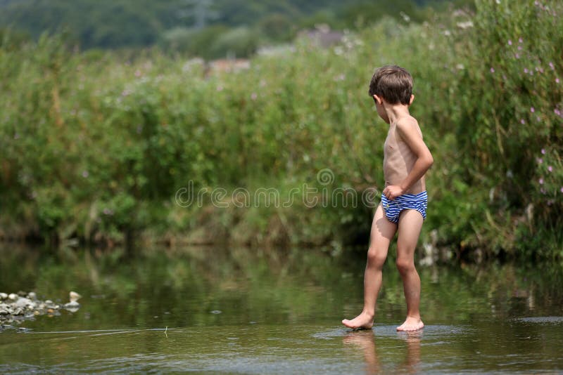 Ragazzo che cammina nei piedi nudi dell'acqua fotografia stock libera da diritti Ragazzo che cammina nei piedi nudi dell'acqua fotografia stock libera da diritti
