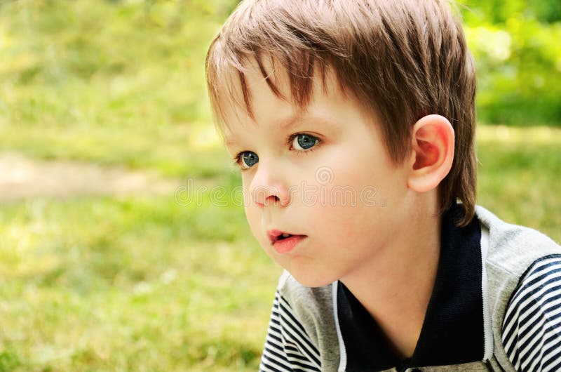 Ragazzo che distoglie lo sguardo con l'interesse nel parco immagine stock Ragazzo che distoglie lo sguardo con l'interesse nel parco immagine stock
