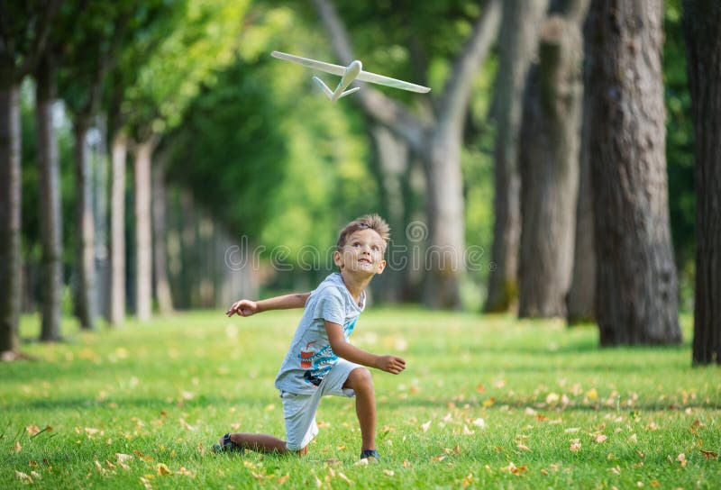 Ragazzo che gioca con l'aliante del giocattolo in parco fotografie stock libere da diritti Ragazzo che gioca con l'aliante del giocattolo in parco fotografie stock libere da diritti