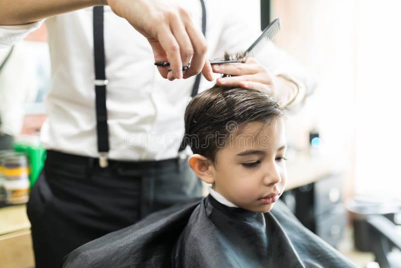 Ragazzo che ha taglio di capelli con il pettine e forbici a Barber Shop immagini stock libere da diritti Ragazzo che ha taglio di capelli con il pettine e forbici a Barber Shop immagini stock libere da diritti