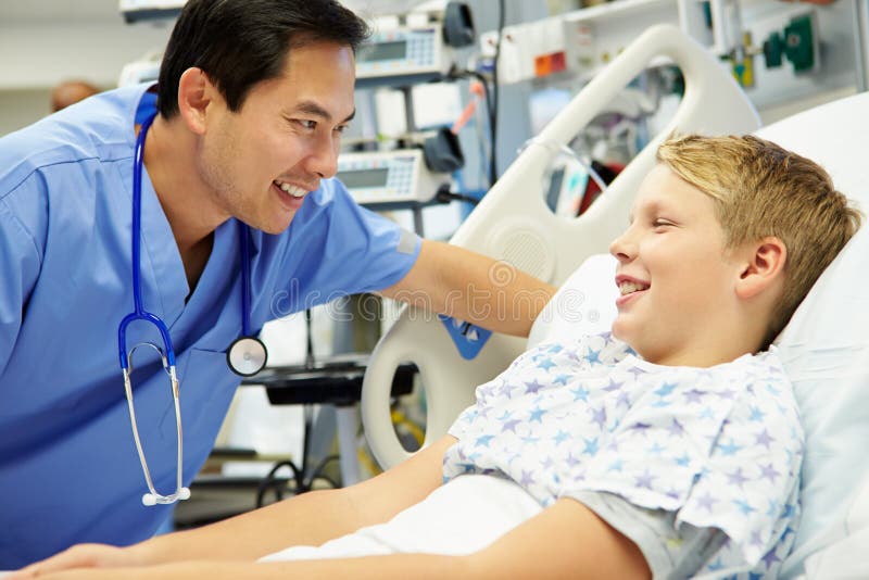 Ragazzo che parla con infermiere maschio In Emergency Room immagini stock Ragazzo che parla con infermiere maschio In Emergency Room immagini stock