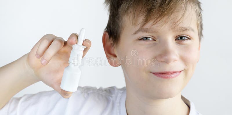 Boy holding nasal spray smiling and looking into the camera on a white background. Boy holding nasal spray smiling and looking into the camera on a white background.