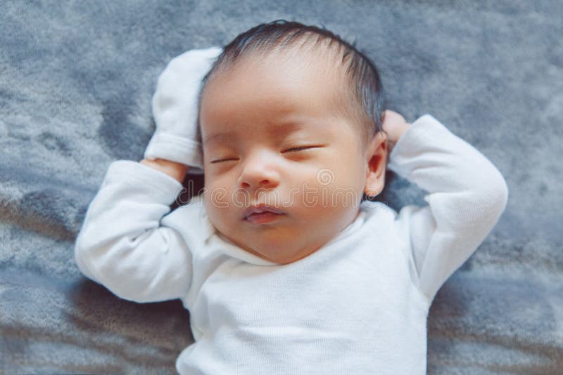 ragazzo cinese asiatico addormentato adorabile della ragazza di neonato della corsa mista che si trova sul letto