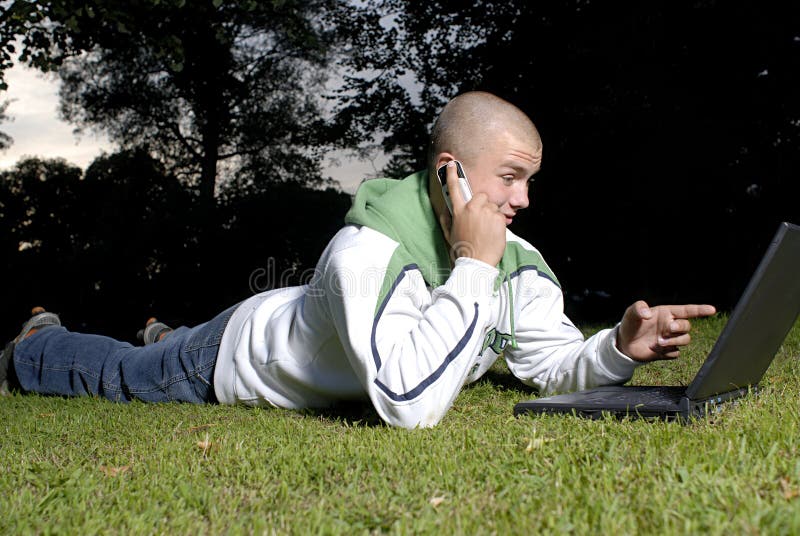 Ragazzo con il telefono delle cellule e del taccuino in sosta fotografie stock libere da diritti Ragazzo con il telefono delle cellule e del taccuino in sosta fotografie stock libere da diritti