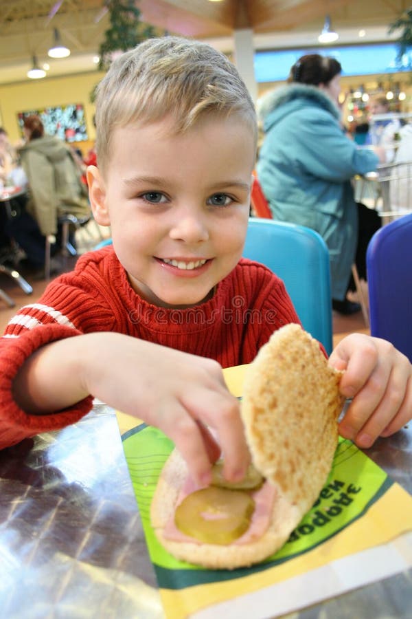 Happy boy with burger in bistro. Happy boy with burger in bistro