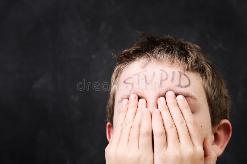 Ragazzo con stupido scritto sulla sua fronte fotografia stock libera da diritti Ragazzo con stupido scritto sulla sua fronte fotografia stock libera da diritti