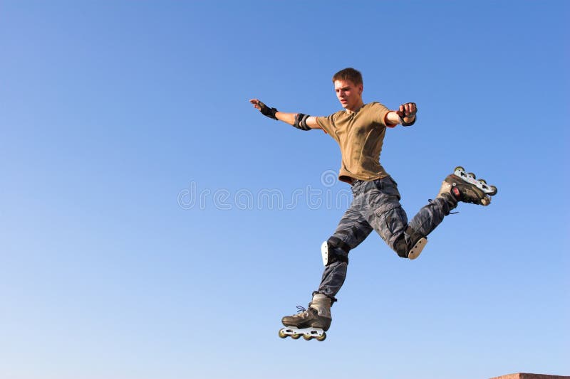 Ragazzo del rullo che salta dal parapetto sul cielo blu fotografie stock Ragazzo del rullo che salta dal parapetto sul cielo blu fotografie stock