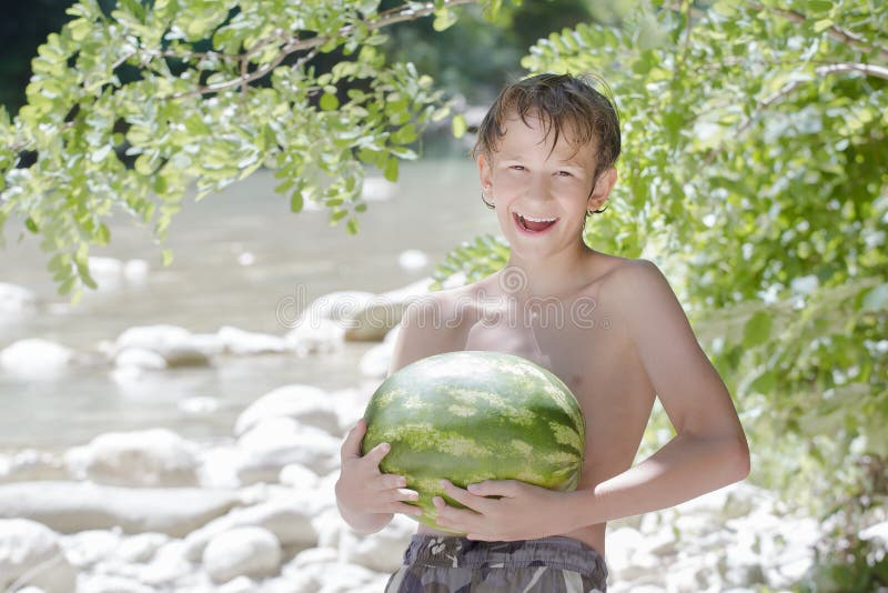 Ragazzo dell'adolescente che tiene anguria verde fresca in mani fotografia stock Ragazzo dell'adolescente che tiene anguria verde fresca in mani fotografia stock