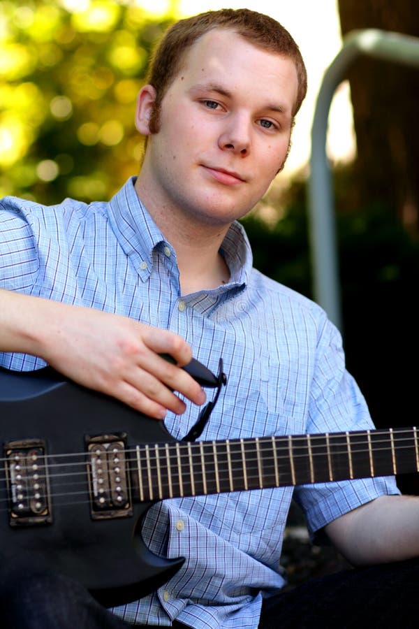 Ragazzo di istituto universitario sveglio con la chitarra fotografia stock libera da diritti Ragazzo di istituto universitario sveglio con la chitarra fotografia stock libera da diritti
