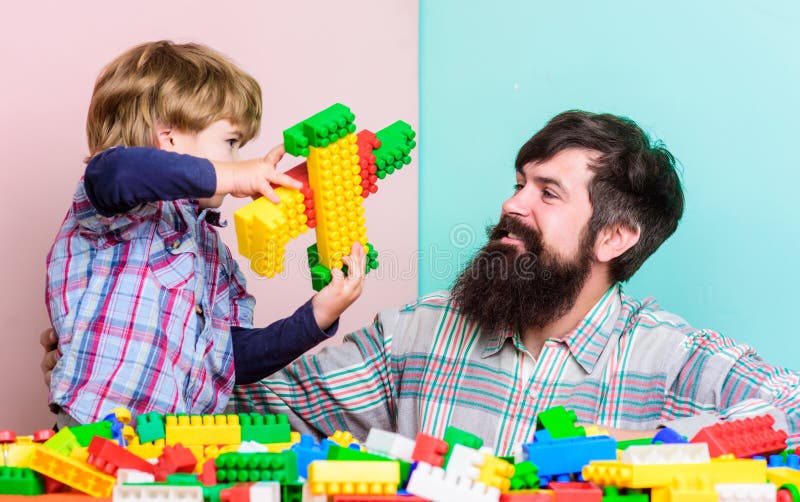 Ragazzo di rappresentazione del capo del padre come sviluppi nel riuscito uomo Pap? e bambino sviluppare i blocchi di plastica E fotografia stock libera da diritti Ragazzo di rappresentazione del capo del padre come sviluppi nel riuscito uomo Pap? e bambino sviluppare i blocchi di plastica E fotografia stock libera da diritti