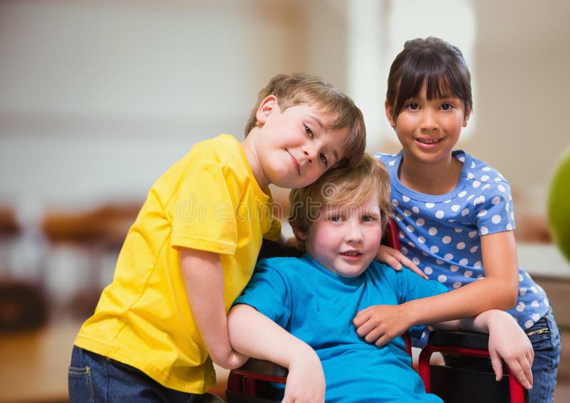 Ragazzo disabile in sedia a rotelle con gli amici nell'aula della scuola fotografie stock Ragazzo disabile in sedia a rotelle con gli amici nell'aula della scuola fotografie stock