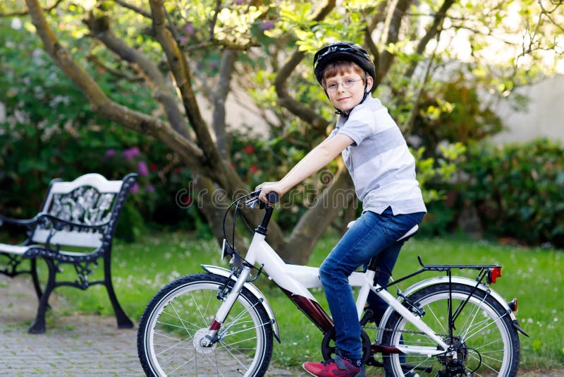 Ragazzo felice del bambino della scuola divertendosi con la guida della bicicletta Bambino in buona salute attivo con il casco di fotografia stock libera da diritti Ragazzo felice del bambino della scuola divertendosi con la guida della bicicletta Bambino in buona salute attivo con il casco di fotografia stock libera da diritti