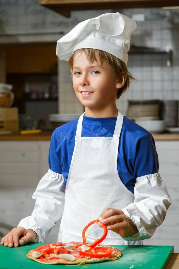 Ragazzo felice divertente del cuoco unico che cucina alla cucina del ristorante immagini stock Ragazzo felice divertente del cuoco unico che cucina alla cucina del ristorante immagini stock