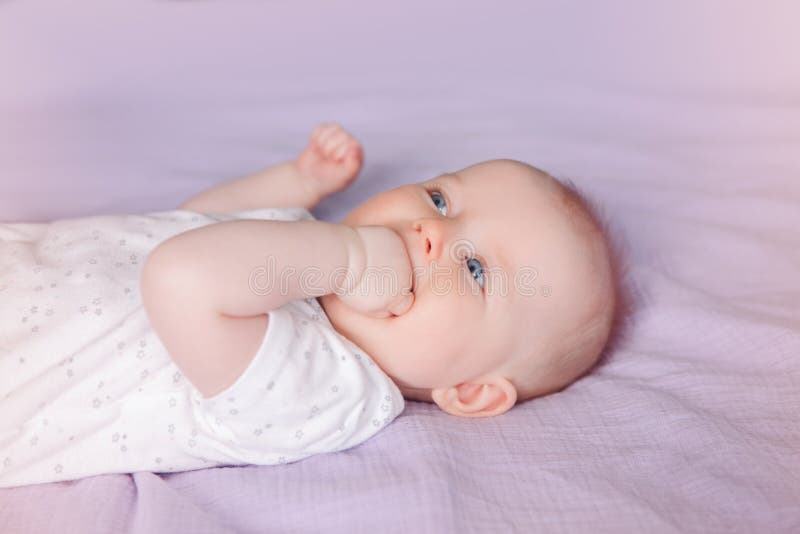 ragazzo infantile caucasico bianco della ragazza del bambino con gli occhi azzurri che si trovano sul letto che lecca succhiando immagini stock libere da diritti ragazzo infantile caucasico bianco della ragazza del bambino con gli occhi azzurri che si trovano sul letto che lecca succhiando immagini stock libere da diritti