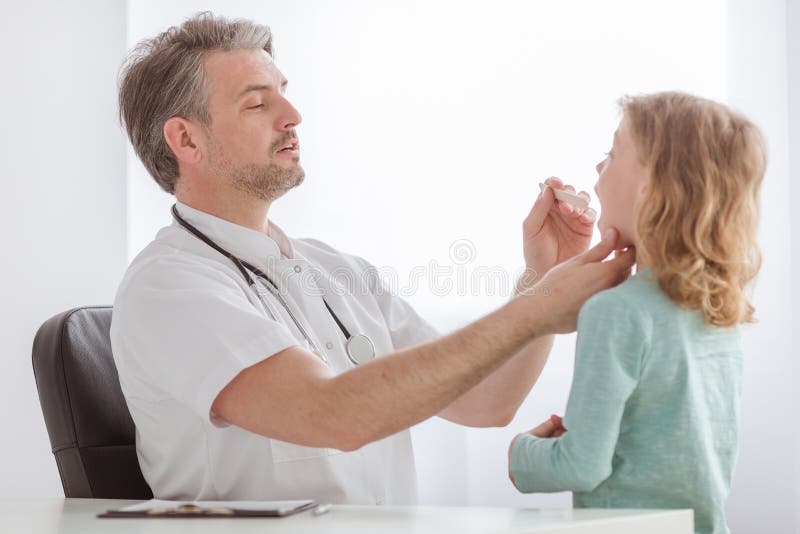 Ragazzo malato con influenza ed il pediatra che controllano la sua gola irritata fotografie stock Ragazzo malato con influenza ed il pediatra che controllano la sua gola irritata fotografie stock
