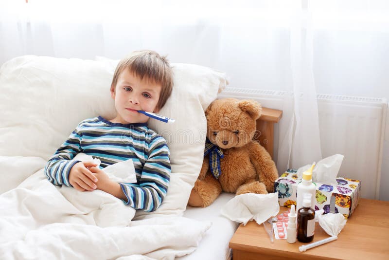 Ragazzo malato del bambino che si trova a letto con una febbre, riposante
