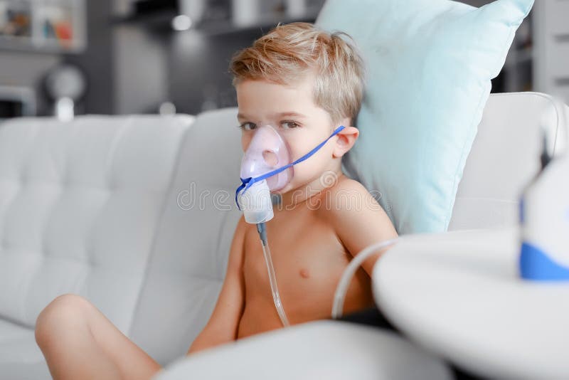 Ragazzo malato nella maschera del nebulizzatore che fa inalazione, procedura respiratoria dalla polmonite o tosse per il bambino