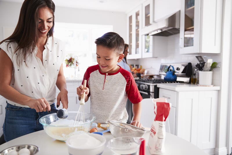 Pre-teen boy making a cake in the kitchen with his mum, close up. Pre-teen boy making a cake in the kitchen with his mum, close up