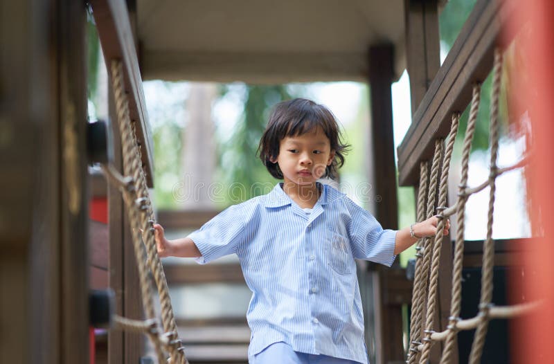 Boy or kid walk on rope in uniform school playing in playground. Boy or kid walk on rope in uniform school playing in playground