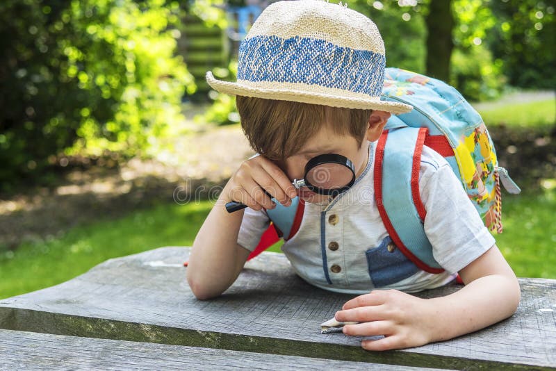 Ragazzo sveglio che gioca con una lente d'ingrandimento immagini stock libere da diritti Ragazzo sveglio che gioca con una lente d'ingrandimento immagini stock libere da diritti