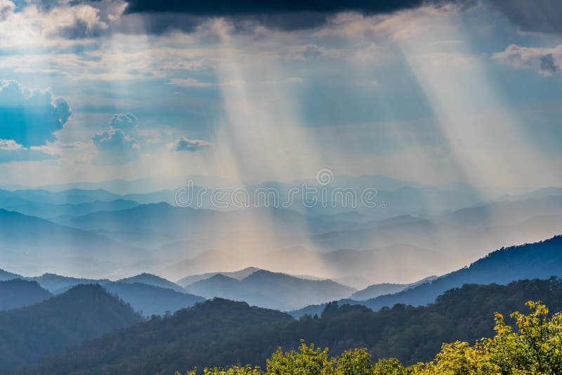 Raggi di cui sopra di Sun delle nuvole che splendono su Ridge Mountains blu