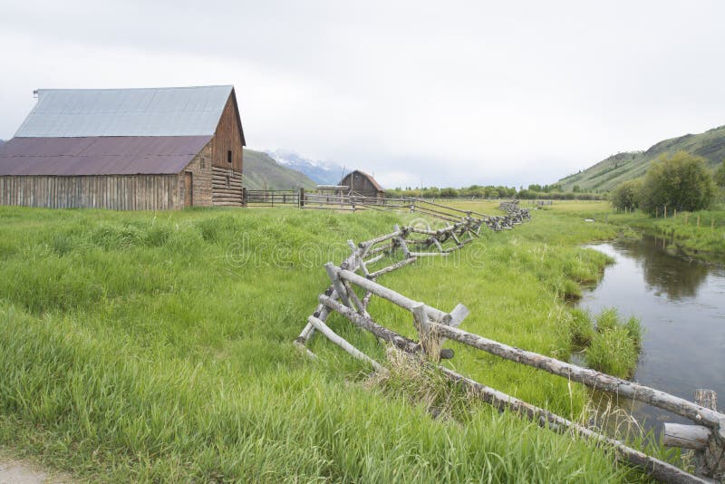 A rail fence leads into an old historic barn.