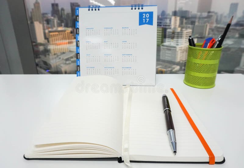 Raillez vers le haut du carnet avec le calendrier 2017 et stationnaire photographie stock Raillez vers le haut du carnet avec le calendrier 2017 et stationnaire photographie stock