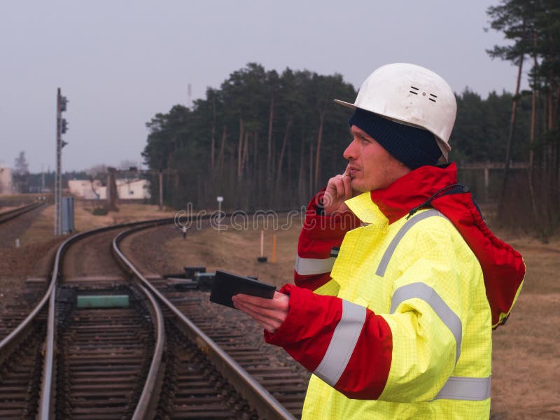 Railroad le travailleur, l'ingénieur dans l'usage protecteur de travail et le casque parlant par le téléphone voies ferrées sur l photographie stock libre de droits Railroad le travailleur, l'ingénieur dans l'usage protecteur de travail et le casque parlant par le téléphone voies ferrées sur l photographie stock libre de droits