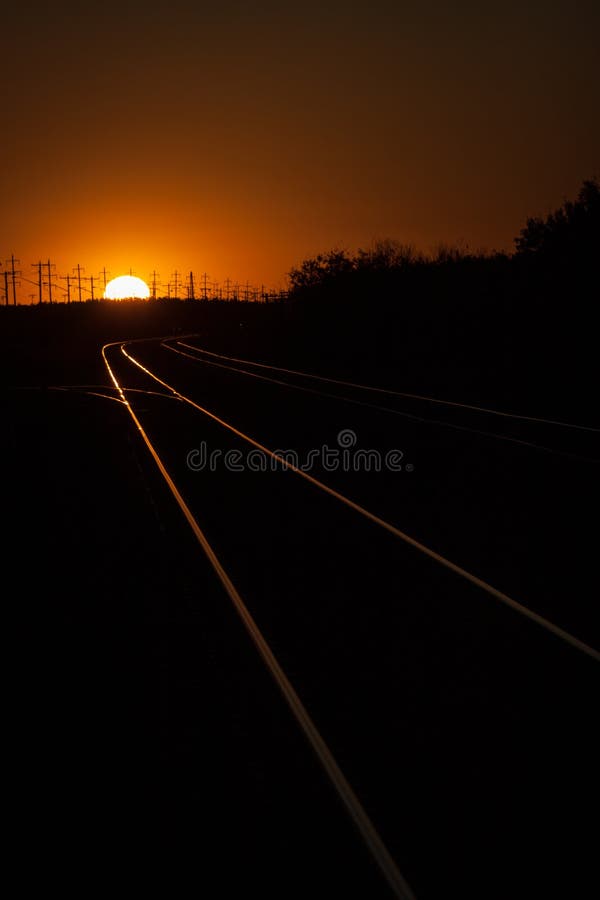 Railroad Tracks Lit During a Golden Summer Sunset. Railroad tracks lit by the setting sun on the horizon royalty free stock image Railroad Tracks Lit During a Golden Summer Sunset. Railroad tracks lit by the setting sun on the horizon royalty free stock image