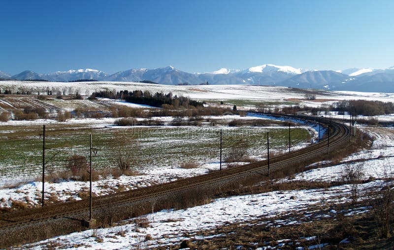 Railroad and winter prairie. Railroad or train tracks passing through open prairie with mountains in the background. Liptov region in Slovakia stock photos Railroad and winter prairie. Railroad or train tracks passing through open prairie with mountains in the background. Liptov region in Slovakia stock photos