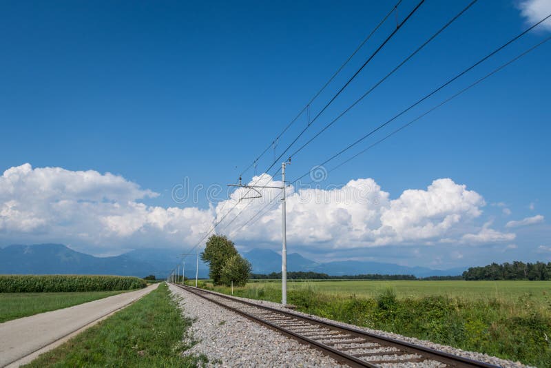 Railway track with power line and countryside road in Slovenia