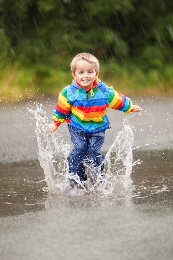 Boy jumping and splashing in rain puddle. Boy jumping and splashing in rain puddle