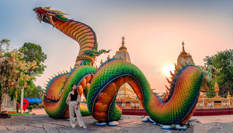 Rainbow carve serpent or colorful Thai Naga and asian woman standing in the sunset at Wat Phra That Nong Bua temple royalty free stock photos