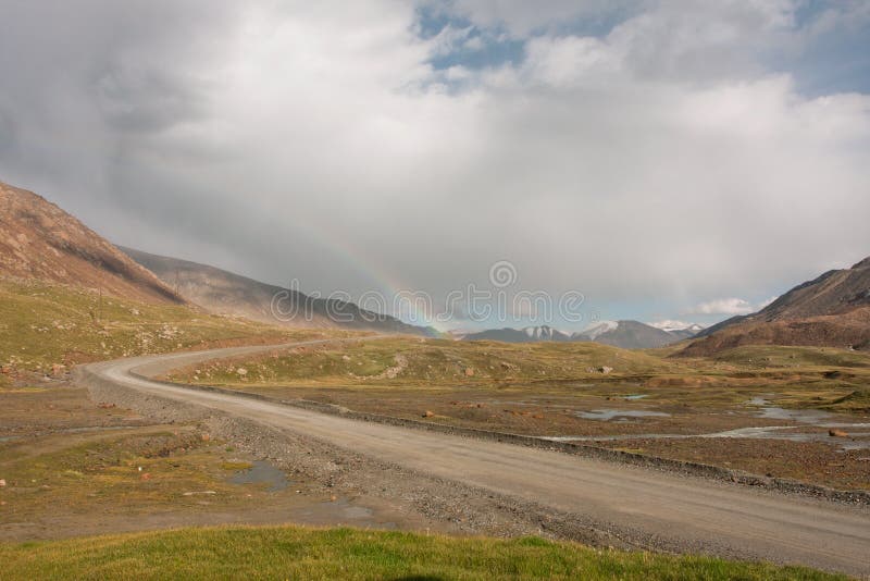 Rainbow in a cloud hanging over rural road between stock photography Rainbow in a cloud hanging over rural road between stock photography