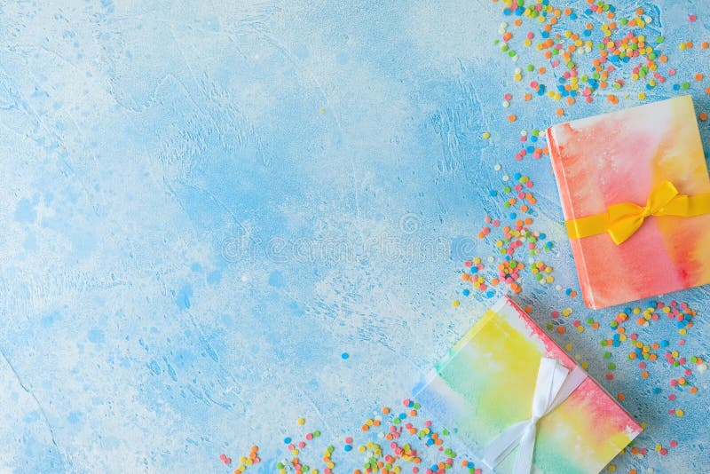 Rainbow Gift Box and Candy Confetti on Blue Background. Flat Lay Stock