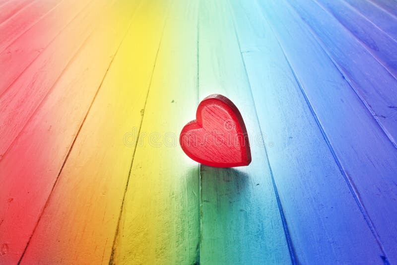 A red love heart on a rainbow wood background. A red love heart on a rainbow wood background.