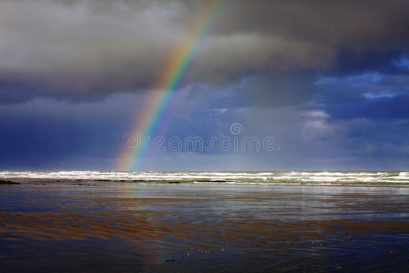 After a night of very heavy rains and thunderstorms, the dark clouds started clearing over the wet and stormy Nye Beach in Newport, creating a dramatic rainbow over the Pacific waves, Newport, Oregon Coast, Pacific Northwest, USA. After a night of very heavy rains and thunderstorms, the dark clouds started clearing over the wet and stormy Nye Beach in Newport, creating a dramatic rainbow over the Pacific waves, Newport, Oregon Coast, Pacific Northwest, USA.