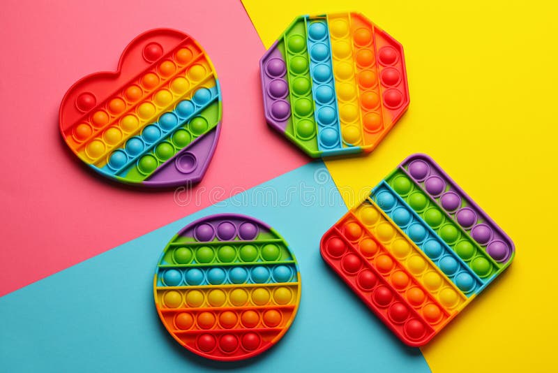 Rainbow pop it fidget toys on color background, flat lay. Rainbow pop it fidget toys on color background