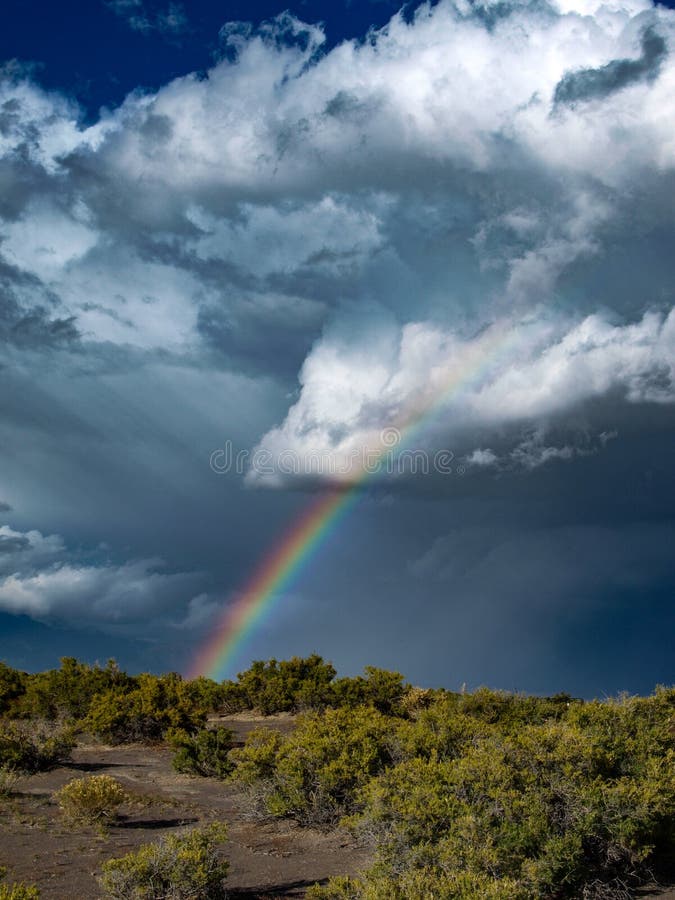 As dark clouds build and threaten to produce a storm a rainbow appears along the edge. As dark clouds build and threaten to produce a storm a rainbow appears along the edge.