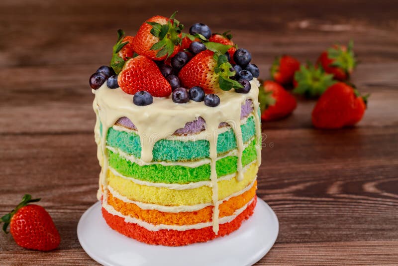 Rainbow sponge cake decorated with fresh berries stock photo