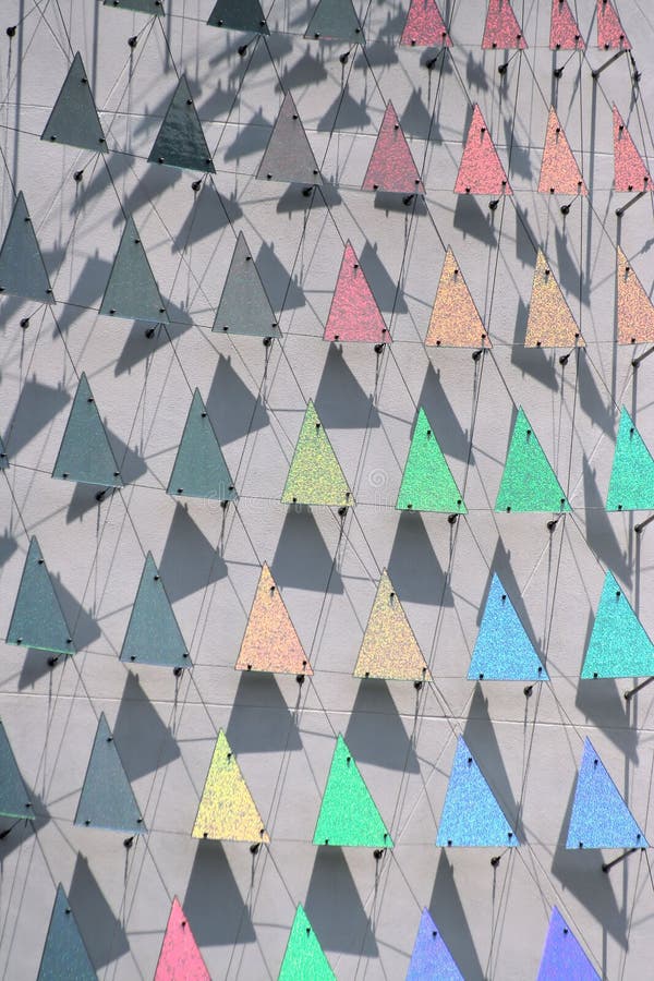 An abstract shot of rows of different colored triangles reflecting the sun with shadows behind them, creating a rainbow of shimmering colors. An abstract shot of rows of different colored triangles reflecting the sun with shadows behind them, creating a rainbow of shimmering colors