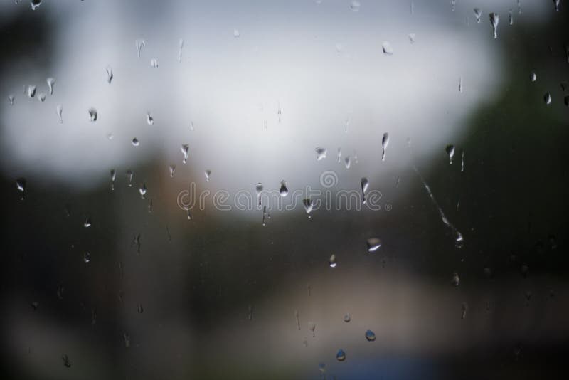 raindrops on a window. Rainy window at night. dark blue wet, drops of water rain on glass background. concept of autumn weather