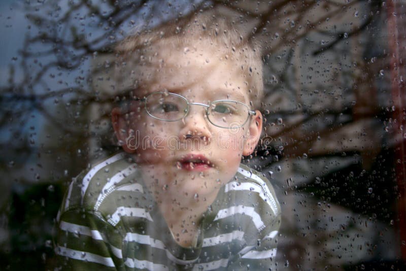 Little boy watching the rain through the window. Little boy watching the rain through the window